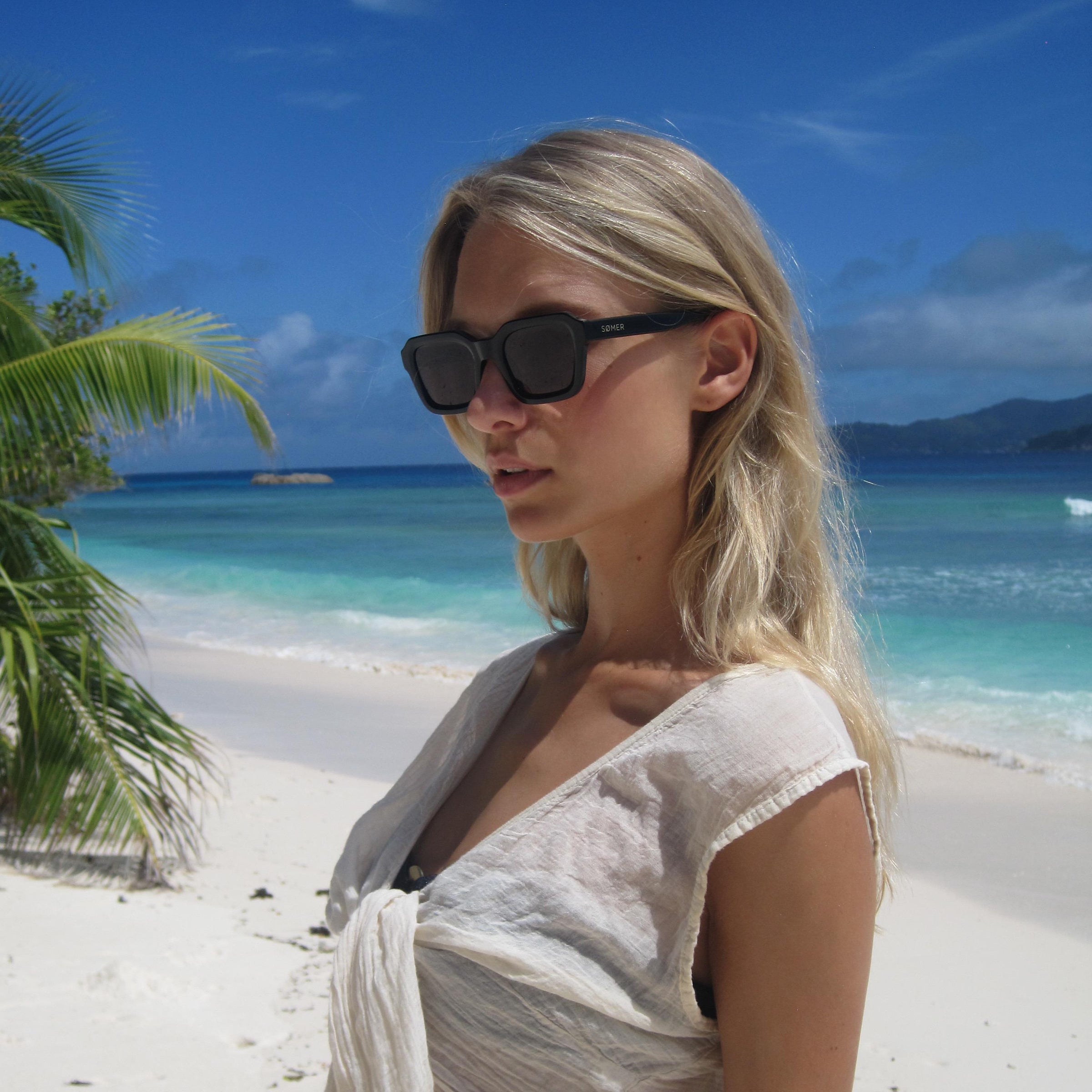 Woman on a tropical beach wearing sunglasses and a cover-up